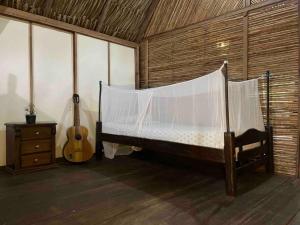 Un dormitorio con una cama y una guitarra en una habitación en Casa Moringa en Palomino