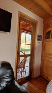 Lipnica WielkaにあるBabiogórskie Domkiのガラスのスライドドア(椅子付)が備わる客室です。