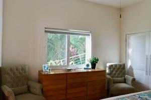a bedroom with a dresser and two chairs and a window at Mandavilla Rose - Inspired USVI - Generator - Starlink in Cruz Bay