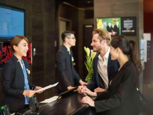 Un gruppo di persone che si aggirano intorno a un bancone di Novotel Taipei Taoyuan International Airport a Dayuan