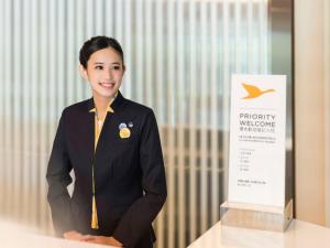 een vrouw in uniform die naast een bord staat bij Novotel Taipei Taoyuan International Airport in Dayuan