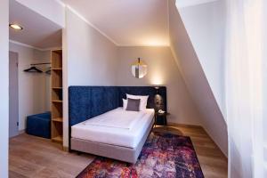 Schlafzimmer mit einem Bett mit blauem Kopfteil und einem Teppich in der Unterkunft Aspire Elements Reutlingen, Trademark Collection by Wyndham in Reutlingen