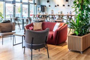 uma sala de estar com um sofá, mesas e cadeiras em Park Inn By Radisson Wismar em Wismar