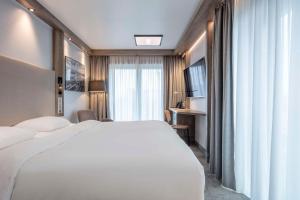 um quarto de hotel com uma cama branca e uma janela em Park Inn By Radisson Wismar em Wismar