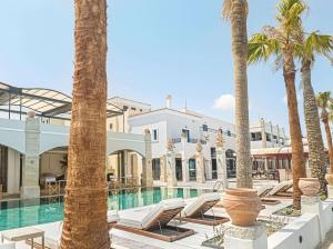 ein Resort mit Palmen und einem Pool in der Unterkunft Grecotel Plaza Beach House in Rethymno