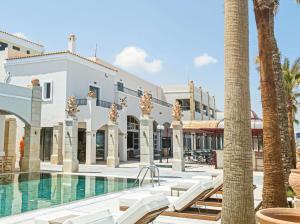 a resort with a swimming pool and palm trees at Grecotel Plaza Beach House in Rethymno Town