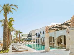 un complejo con piscina y palmeras en Grecotel Plaza Beach House, en Rethymno