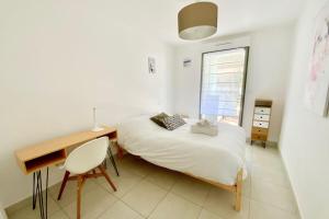 1 dormitorio con cama, escritorio y ventana en Le Sublime- Vue climatisation et parking ! en Montpellier
