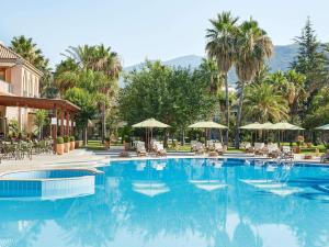 una grande piscina con sedie e ombrelloni di Grecotel Filoxenia Hotel a Kalamáta