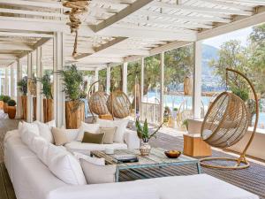 a living room with white furniture and large windows at Grecotel Filoxenia Hotel in Kalamata