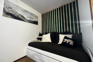 een slaapkamer met een bed met zwart-witte kussens bij The Edelweiss- Renovated studio for 4 people! in Chamrousse