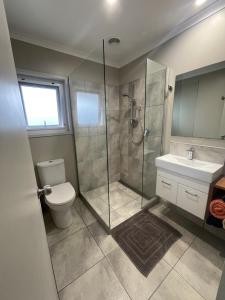 a bathroom with a shower and a toilet and a sink at Guest Wing in Richmond Downs in Walton