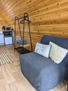 Sea Crest Pods في روسنوولاغ: غرفة معيشة مع أريكة زرقاء وجدار خشبي