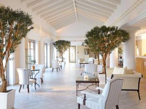 a lobby with tables and chairs and trees at Grecotel La Riviera & Aqua Park in Loutra Killinis