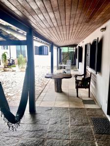 a patio with a table and a hammock in a house at Baluarte Suites in Búzios