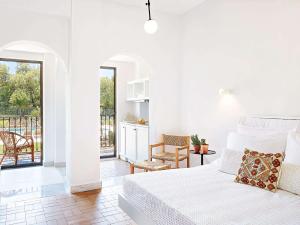 a white bedroom with a bed and a balcony at Villa Oliva in Adelianos Kampos