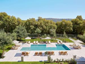 uma piscina com cadeiras e guarda-sóis ao lado de um resort em Villa Oliva em Adelianos Kampos