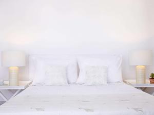シッシにあるGrecotel Meli Palaceの白い枕とランプ2つ付きの白いベッド