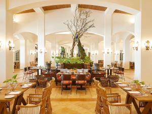 a restaurant with wooden tables and chairs in a room at Grecotel Olympia Oasis & Aqua Park in Loutra Killinis
