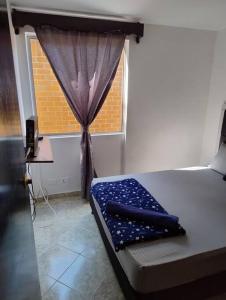 ein Schlafzimmer mit einem Bett und einem Fenster mit einem Vorhang in der Unterkunft comodidad y ubicación. in Medellín