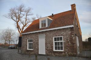 ein Backsteinhaus mit einer weißen Tür und Fenstern in der Unterkunft Vakantiehuis 't Verloren Schaap Sluis in Sluis