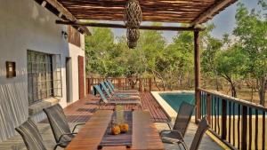 a deck with a table and chairs next to a pool at Greater Kruger View - Luxury Bush Villa in Marloth Park