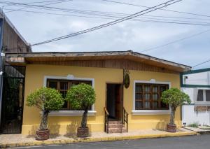 żółty dom z dwoma drzewami przed nim w obiekcie HOSTAL RIVAS INNS w mieście Rivas