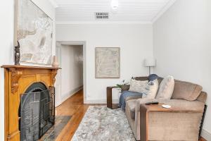 a living room with a couch and a fireplace at 'Violet Cottage' An Idyllic Urban Oasis for Two in Unley