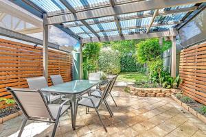 a patio with a table and chairs under a pergola at 'Violet Cottage' An Idyllic Urban Oasis for Two in Unley