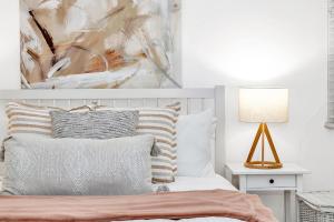 阿德莱德'Violet Cottage' An Idyllic Urban Oasis for Two的卧室里有一张床，墙上挂着一幅画