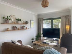 a living room with a couch and a flat screen tv at Sanddune Delight in Papamoa