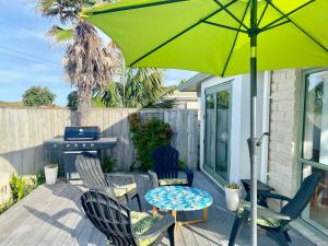 eine Terrasse mit 2 Stühlen und einem Tisch mit einem Sonnenschirm in der Unterkunft Sanddune Delight in Papamoa