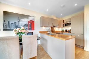a kitchen with white cabinets and a table with a vase of flowers at Modern 2Bed 2Bath Apartment Tower Bridge London Bridge - Perfect For Long Stays in London