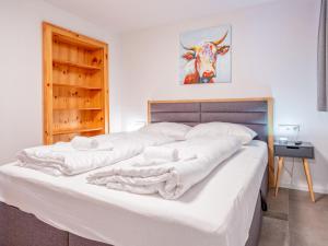 Un dormitorio con una gran cama blanca con una vaca en la pared en Selbhorn, en Hinterthal