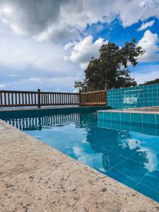 a swimming pool with blue tile and a wooden fence at Chalés do alegre in Capitólio