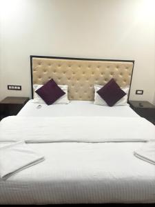 a large bed with white sheets and purple pillows at Hotel heaven by sky in Calangute
