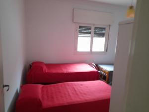 three red beds in a room with a window at Alquiler de Casa en Cosquin temporario in Cosquín