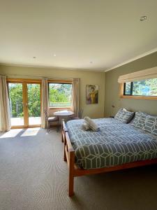 a bedroom with a bed and a table and windows at Parautane Lodge in Nelson