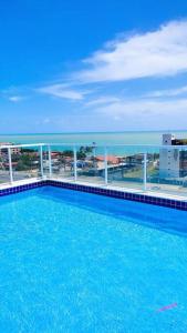 uma piscina no topo de um edifício com o oceano em APTO - perto da praia - Piscina - Cabedelo João Pessoa em Cabedelo