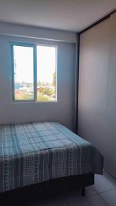 um quarto com uma cama e duas janelas em APTO - perto da praia - Piscina - Cabedelo João Pessoa em Cabedelo