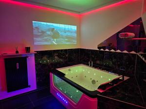 jacuzzi en una habitación con luces púrpuras en Magnifique Suite Spa Luxembourg, en Differdange