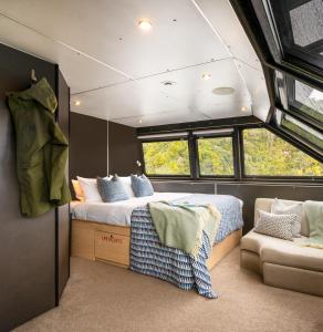 ein Schlafzimmer mit einem Bett und einem Sofa in einem Zimmer in der Unterkunft Milford Sound Overnight Cruise - Fiordland Discovery in Milford Sound