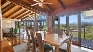 a dining room with a table and chairs and windows at Rainforest Treehouse Sanctuary - with ocean views in Smithfield