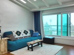 a living room with a blue couch and a large window at Aewol Gwangryeong House in Jeju