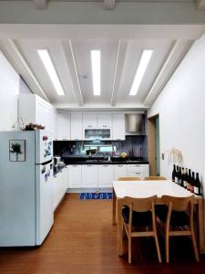 a kitchen with a table and a white refrigerator at Aewol Gwangryeong House in Jeju