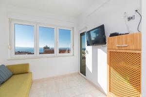 ein Wohnzimmer mit einem Sofa, einem TV und Fenstern in der Unterkunft Apartments with a parking space Makarska - 22017 in Makarska