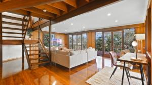 a living room with a couch and a staircase at Rainforest Treehouse Sanctuary - with ocean views in Smithfield