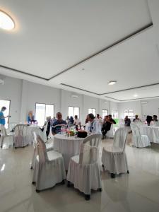 un salón de banquetes con mesas blancas y sillas blancas en Hotel Asri Baru en Purwokerto