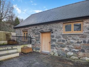 a stone house with a wooden door and windows at The Aran - Uk46080 in Frongoch