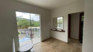 een lege woonkamer met een groot raam en een tafel bij Linda casa triplex 50 metros do mar in Governador Celso Ramos